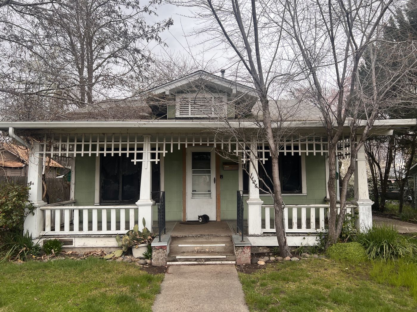 The same green Medford house on the day it was purchased, with a bare winter yard and an overgrown walkway